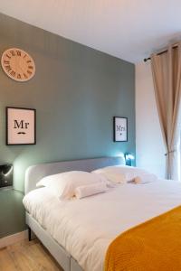een slaapkamer met een groot bed met een klok aan de muur bij Le chevremont in Metz