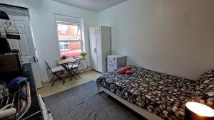 a bedroom with a bed and a table and a window at SMALL COZY STUDIO ZONE 1 LONDON in London