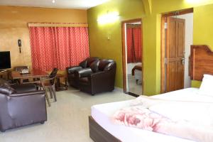 um quarto de hotel com uma cama e uma sala de jantar em Hotel Sri Balaji em Ooty