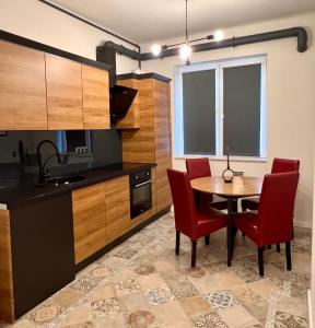 uma cozinha com uma mesa de madeira e cadeiras vermelhas em Dream Home em Turda