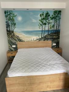 a bedroom with a bed with a painting of a beach at Apartament Szałwiowy Dębina in Debina