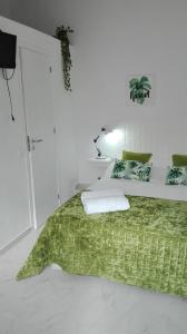a bedroom with a bed with a green blanket at JB House in Nazaré