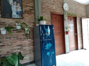 niebieska lodówka z kwiatami pomalowanymi obok ściany z cegły w obiekcie Bua Guest House w mieście Medan