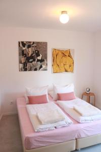 a bedroom with a pink bed with two pictures on the wall at Bedebike in Óbidos