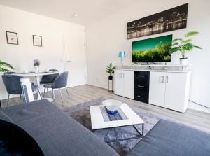 a living room with a couch and a tv on a wall at City Suite - 5 Min to HBF in Mannheim