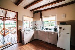 a kitchen with a white refrigerator and some windows at Domek na skarpie in Szczybały Giżyckie