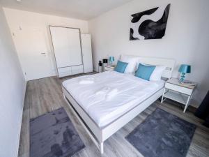 a bedroom with a large white bed with blue pillows at City Suite - 5 Min to HBF in Mannheim