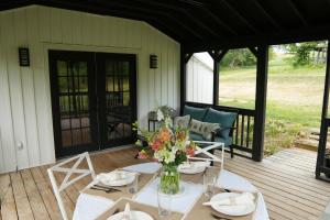- une table avec un vase de fleurs sur une terrasse couverte dans l'établissement The Inn at Terra Farms, à Glen Rock