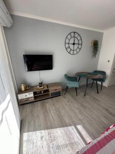 a living room with a tv and a table and a clock at STUDIO APARTMAN PAVIĆ in Vinkovci