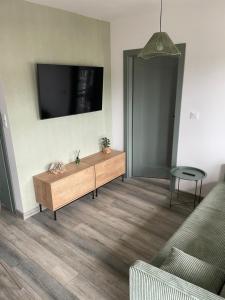 a living room with a couch and a tv on the wall at Apartament Szałwiowy Dębina in Debina