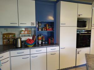 una cocina con armarios blancos y una pared azul en Chez l'Eveline, en Les Bois