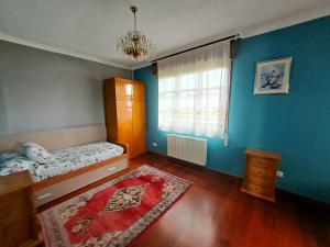 - une chambre avec des murs bleus, un lit et une fenêtre dans l'établissement Casa Chalet, Villa Elisa, à Gijón
