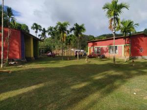een tuin met palmbomen en een rood gebouw bij Trident Jungle Stay in Dandeli