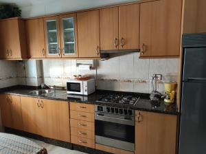 a kitchen with wooden cabinets and a stove and a microwave at Fonte do Cabo in Muxia