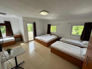 a bedroom with two beds and a table and windows at Vila Dzenana Boracko Jezero in Konjic