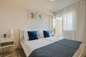 a white bedroom with a large bed with blue pillows at 3Level Apartments Kroatien in Umag