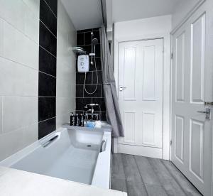 een witte badkamer met een bad en een wastafel bij Rustic Rhondda Retreat with Hot Tub & Sauna - Ystrad in Llwyn-y-pia