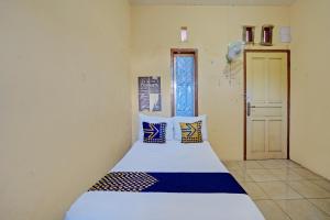 SPOT ON 92730 Lili Kost Syariah في بانيووانجى: غرفة نوم مع سرير ووسائد زرقاء وبيضاء