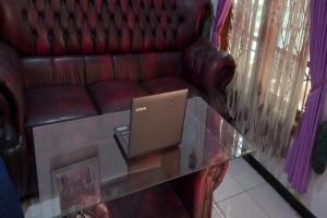 een glazen tafel met een bank en een laptop erop bij SPOT ON 92743 Kost Elisabeth Syariah in Ngadipuro