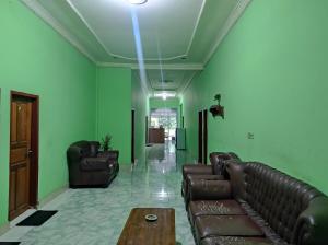 a living room with leather couches and a coffee table at OYO 92724 Penginapan Syariah Al Syifa in Kendari