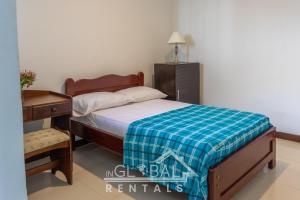 1 dormitorio con 1 cama con manta azul y blanca en Sandalio Hostal Cali, en Cali