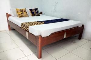 ein Bett mit einem Holzrahmen in einem Zimmer in der Unterkunft SPOT ON 92743 Kost Elisabeth Syariah in Ngadipuro