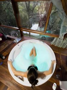a woman laying in a bath tub in a window at Pousada Vale das Orquídeas in Lavrinhas