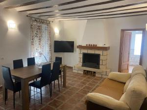 un soggiorno con divano, tavolo e camino di Agradable casa con chimenea interior y barbacoa. a Graja de Iniesta