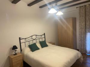 una camera con un letto bianco con due cuscini verdi di Agradable casa con chimenea interior y barbacoa. a Graja de Iniesta Altre 26 foto