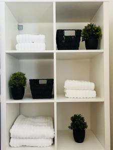 a white shelf with baskets of towels and plants at Coastal Apartments No 2 in Seaham