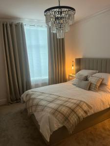 a bedroom with a large bed and a chandelier at Coastal Apartments No 2 in Seaham