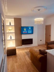 a living room with a couch and a television on a wall at Coastal Apartments No 2 in Seaham