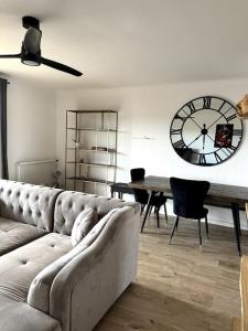 a living room with a couch and a clock on the wall at Appartement Cosy Calao - Parking fermé gratuit in Perpignan