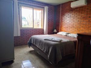 a bedroom with a bed and a brick wall at Casa aconchegante em Canela in Canela