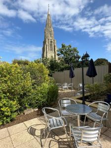 una mesa y sillas con un campanario de iglesia en el fondo en Queensmead Hotel, en Shanklin