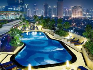 a swimming pool on top of a building with a city skyline at Hotel Indonesia Kempinski Jakarta in Jakarta