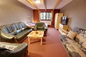 a living room with leather couches and a tv at PENZION HARRY na sjezdovce KRKONOŠE in Vysoké nad Jizerou