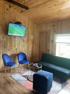 sala de estar con sofá, 2 sillas y TV en Cabañas Rio Pangal en Puerto Aisén