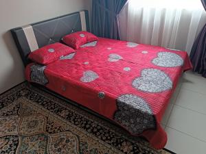 1 cama con edredón rojo y almohadas en Aisy Homestay Putrajaya Cyberjaya KLIA en Kampung Dengkil