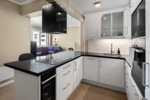 a kitchen with white cabinets and a black counter top at 2 min to Bryggen - Rooftop - Office with 49" Screen in Bergen