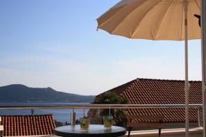 a table with an umbrella and a chair and water at Apartments Grković Trsteno Adventure Experience Accommodation 1 in Dubrovnik