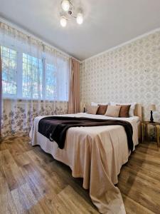 ein Schlafzimmer mit einem großen Bett und einem großen Fenster in der Unterkunft Золотой квадрат in Almaty