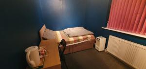 a small bedroom with a bed in a blue room at private room with free parking close to lake side in West Thurrock