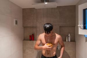 a man standing in a shower with water pouring from his head at Haus Anni in Immenstaad am Bodensee