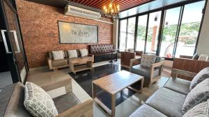 uma sala de estar com um sofá e cadeiras e uma parede de tijolos em Buathong Pool Villa em Ban Khung Taphao