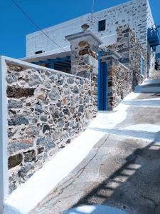 eine Steinmauer neben einem Gebäude mit blauer Tür in der Unterkunft Queen Stampalia in Astypalea-Stadt