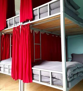 two bunk beds in a room with red curtains at Hugo's Family in Da Lat