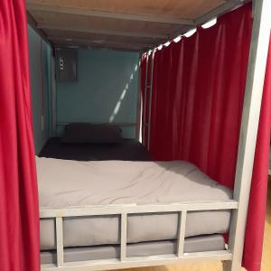 Bett in einem Zimmer mit roten Vorhängen in der Unterkunft Hugo's Family in Da Lat