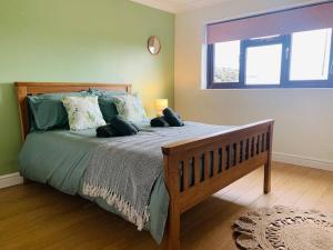 a bedroom with a bed with green sheets and a window at Welsh cottage coastal retreat with stunning views in Pen-y-groes