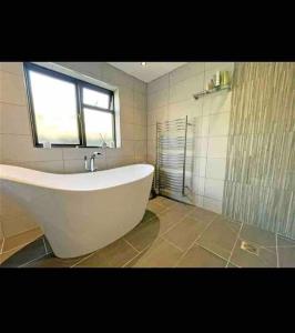 a white bath tub in a bathroom with a window at Welsh cottage coastal retreat with stunning views in Pen-y-groes